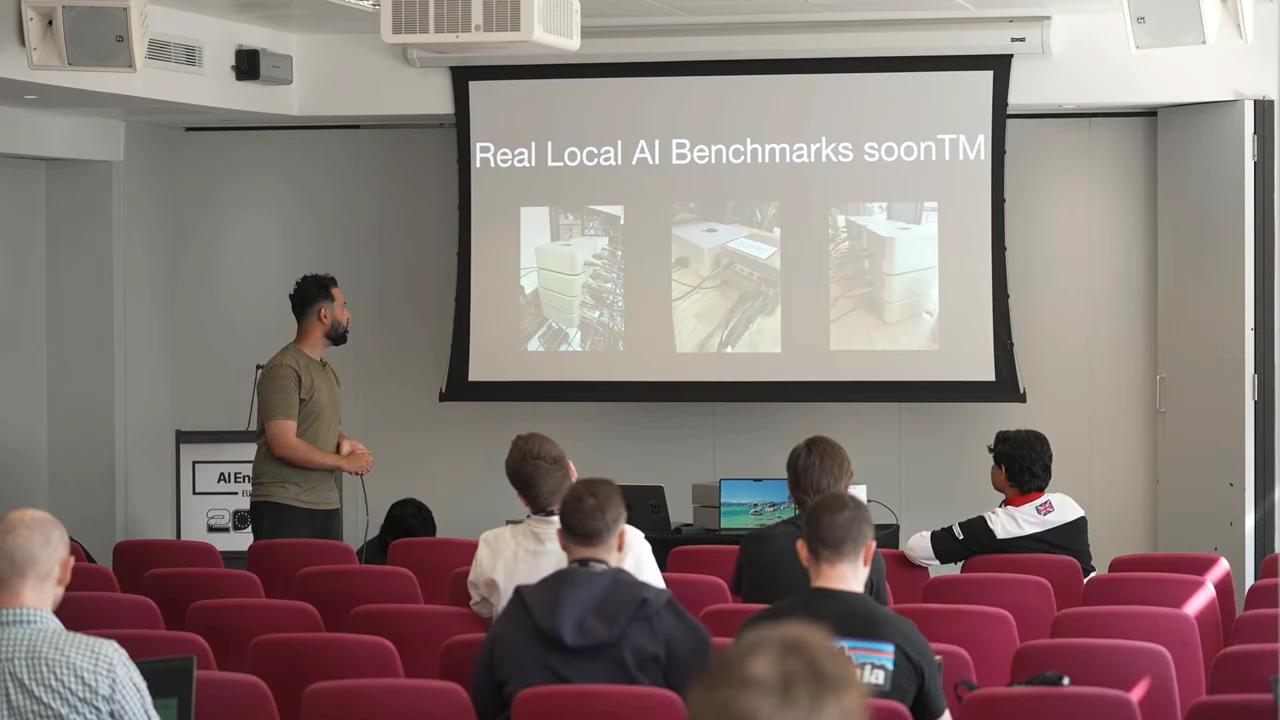Presenter beside a slide showing three hardware photographs under “Real Local AI Benchmarks soonTM.”