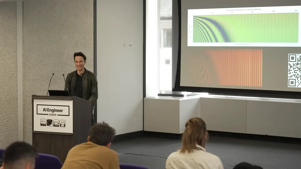 Projected slide shows a green-and-blue sinusoidal positional encoding heatmap above an orange striped pattern, with a QR code at right and the speaker at the lectern.