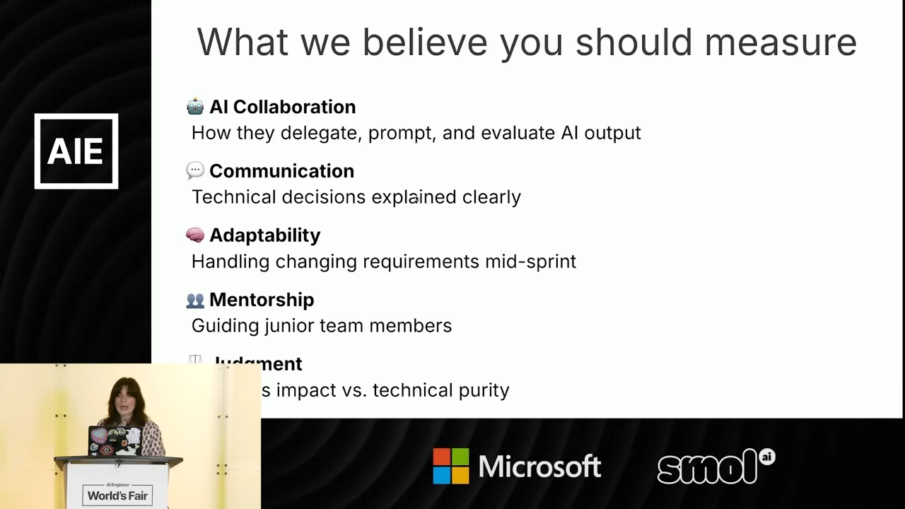 Slide titled “What we believe you should measure” describes delegating, prompting and evaluating AI output; explaining technical decisions; handling changing requirements; and guiding junior team members. The speaker inset partly obscures the final judgment item.