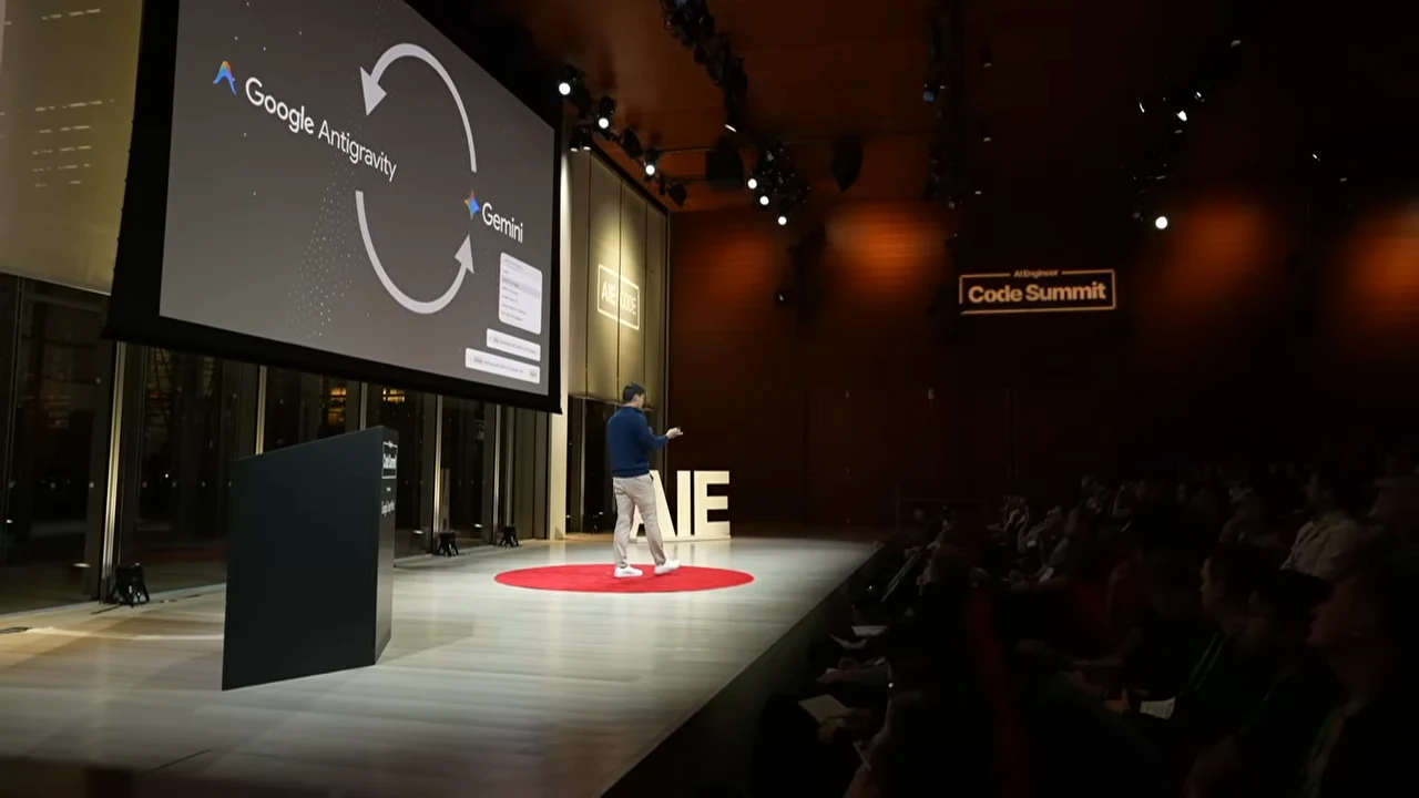 A wide stage view shows a projected slide with Google Antigravity and Gemini linked by two large curved arrows.