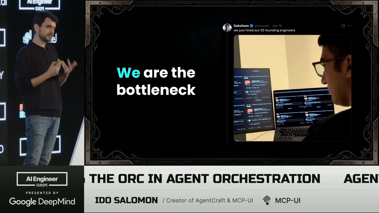 The presenter stands beside a slide reading “We are the bottleneck,” with a photo of a person facing several screens.