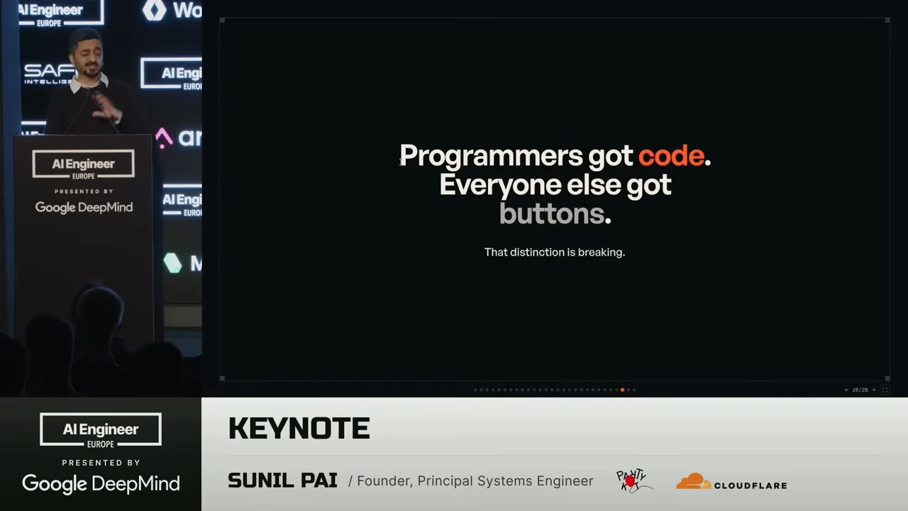 Slide reading “Programmers got code. Everyone else got buttons.” with “That distinction is breaking.” underneath, beside the speaker.