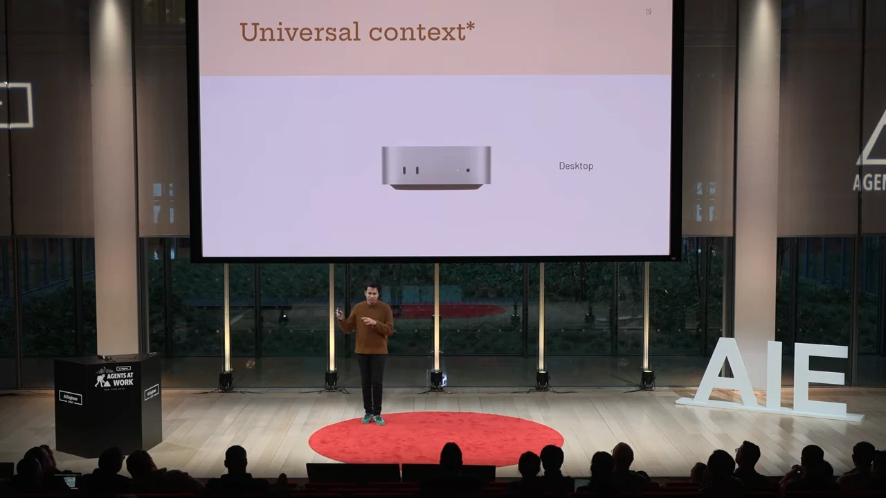 Projected slide titled “Universal context*” showing a small silver desktop computer and the label “Desktop,” with the speaker below.