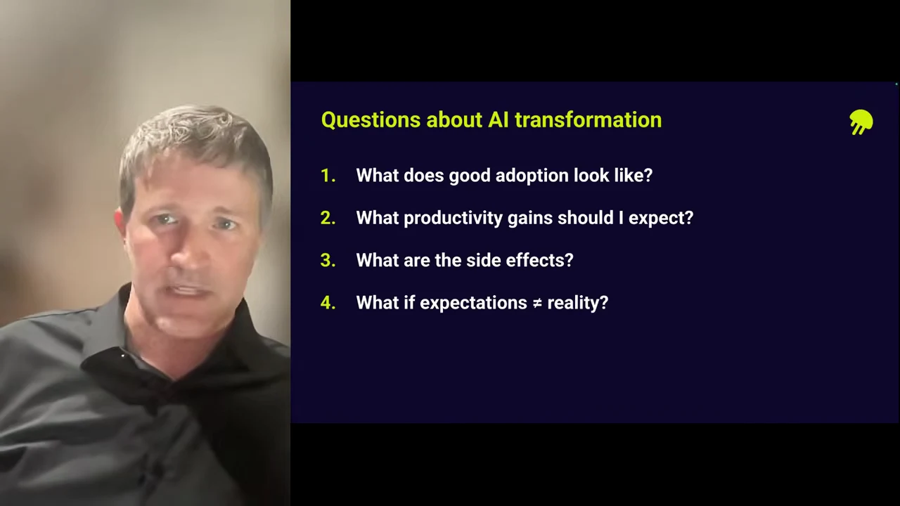 Speaker beside a slide listing four questions: What does good adoption look like? What productivity gains should I expect? What are the side effects? What if expectations ≠ reality?