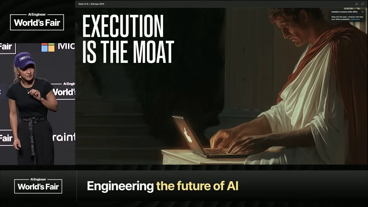 Slide reading “EXECUTION IS THE MOAT” beside an illustration of a robed figure using a laptop, with the speaker at left.