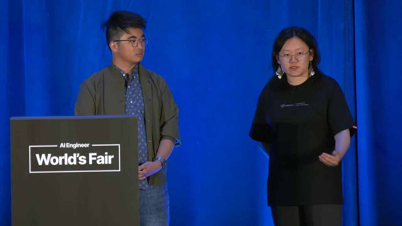 Two panelists beside a World's Fair lectern against blue curtains; the panelist on the right gestures toward the audience.