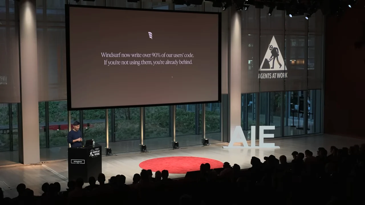 Stage view with a projected slide saying Windsurf writes over 90% of users’ code and that those not using it are already behind.
